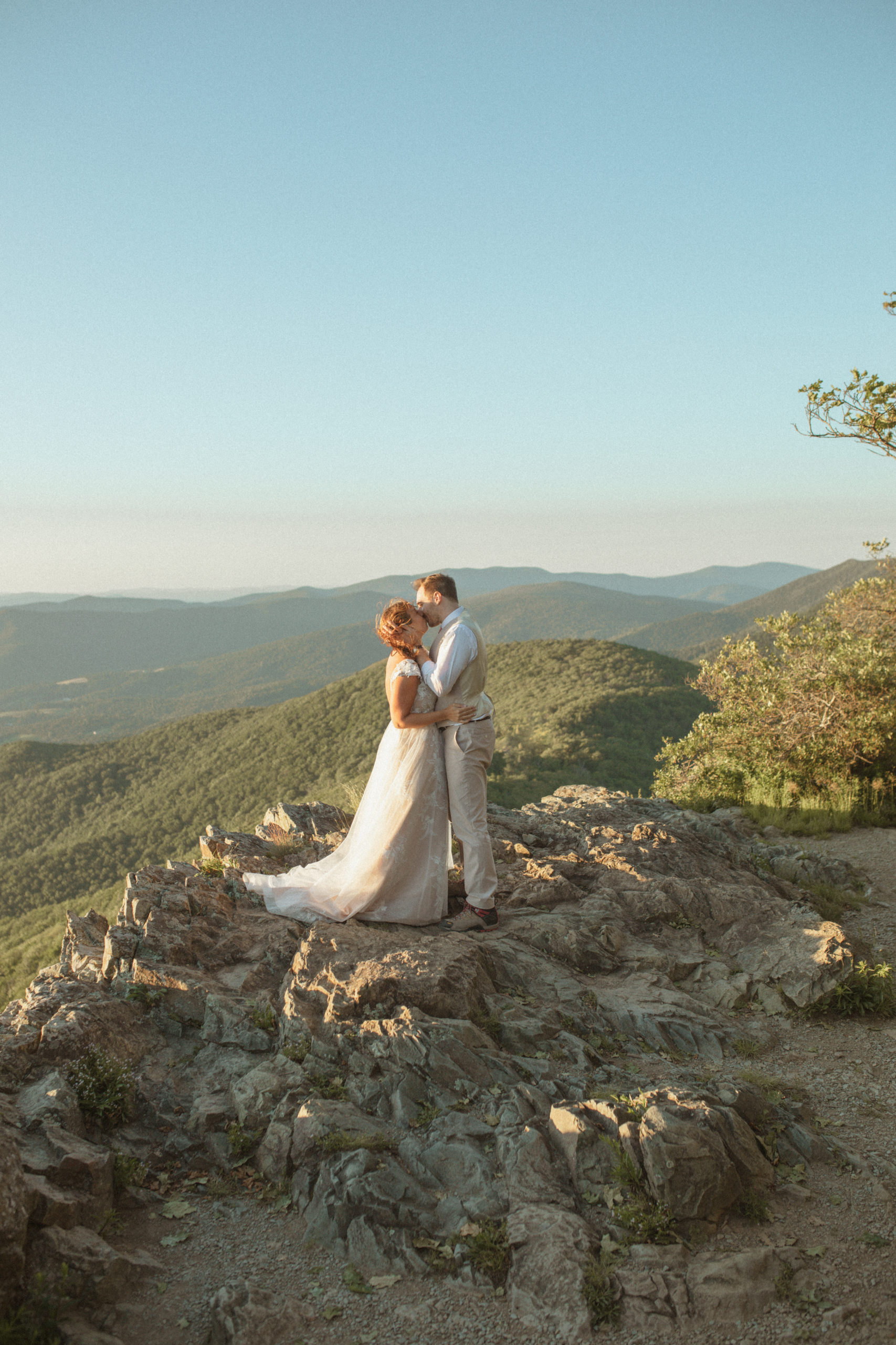 Shenandoah National Park wedding with bride and groom standing on a mountains top kissing with the valley behind them captured by Virginia wedding photographer
