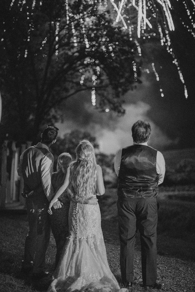 Virginia wedding photographer captures bride and groom holding hands and watching fireworks