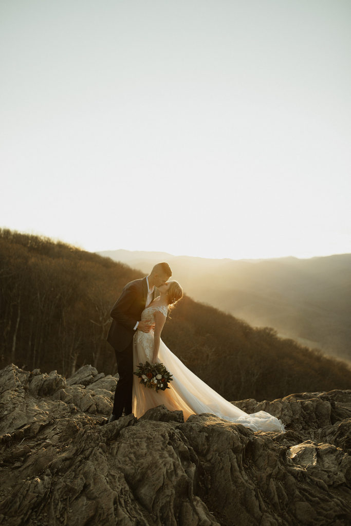 adventure wedding at sunset on top of a mountain with groom dipping back his bride and passionately kissing her captured by Virginia wedding photographer