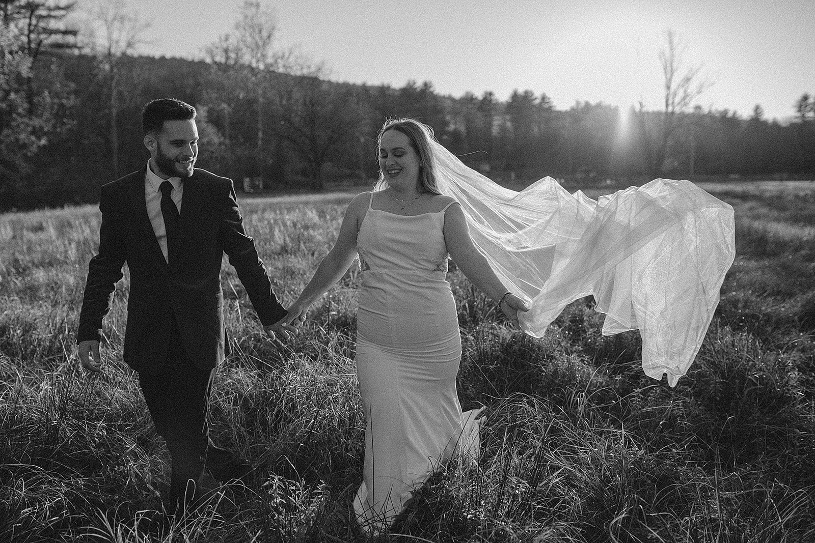 bride and groom holding hands and walking through a meadow at sunset for their outdoor elopement with Charlottesville wedding photographer