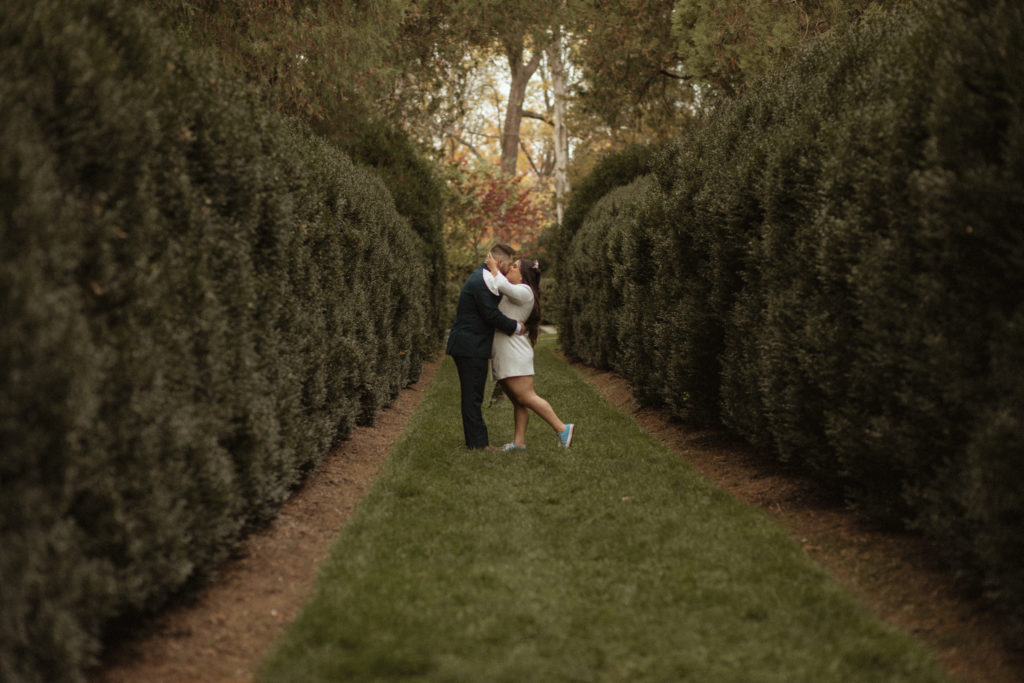 outdoor engagement photos in a courtyard garden with man and woman embracing and kissing each other photographed by Charlottesville wedding photographer 