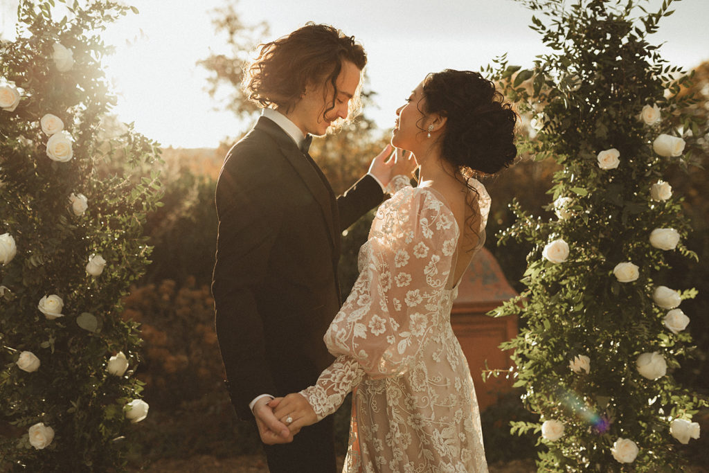 Charlottesville wedding photographer captures bride and groom dancing at sunset together surrounded by their white roses for an outdoor wedding 