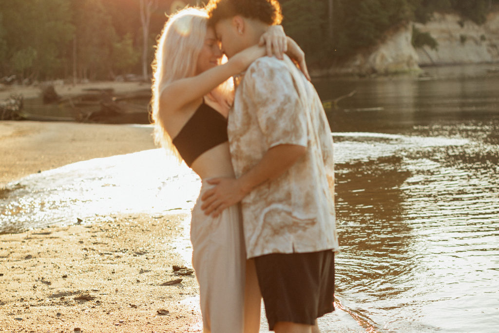 man and woman embracing on a lakes beach for their Virginia engagement photos