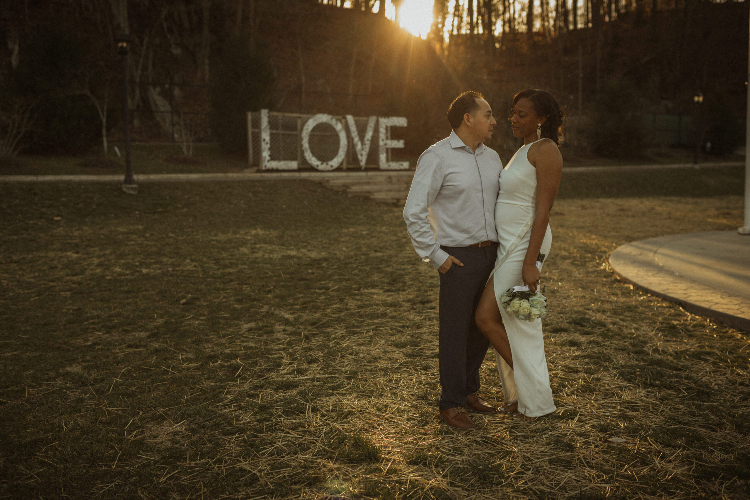 Elopement couple standing in front of the Virginia LOVE sign at Occoquan Park.