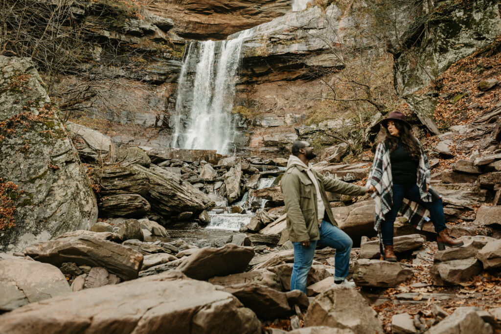 Couple standing at different heights in front of a waterfall and Shenandoah National Park