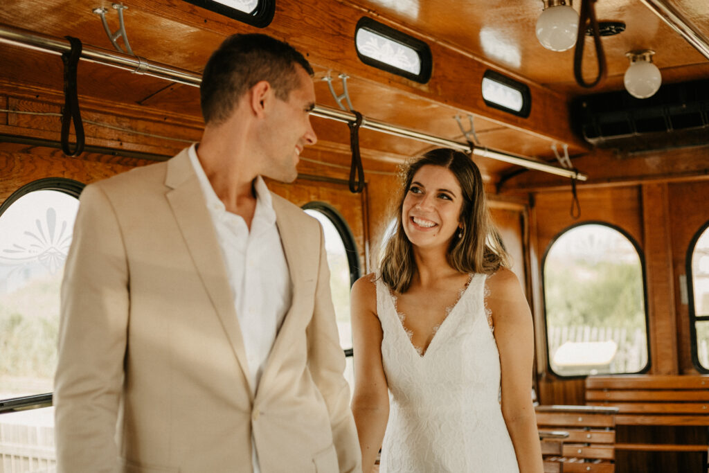 Couple standing in a box car holding hands walking down the aisle as they look at one another