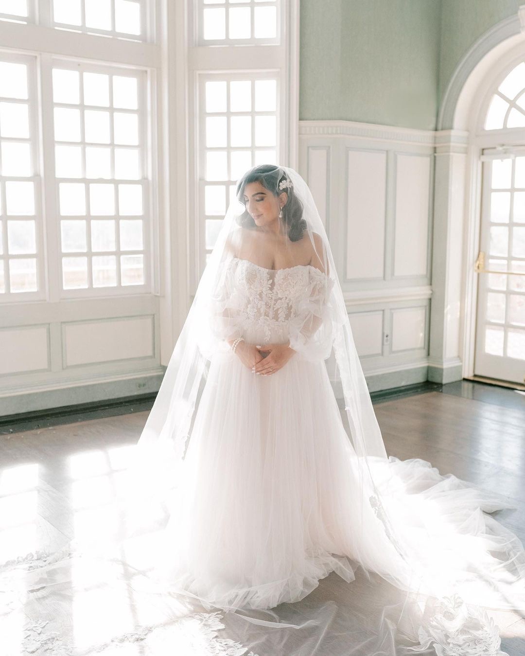 Bride standing in a sunlit room wearing a long ethereal wedding gown from Tiffanys Bridal in Richmond Virginia