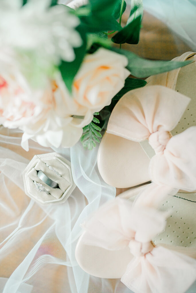 Image of the light pink bow shoes, rings, and bridal flowers. Detail shot.