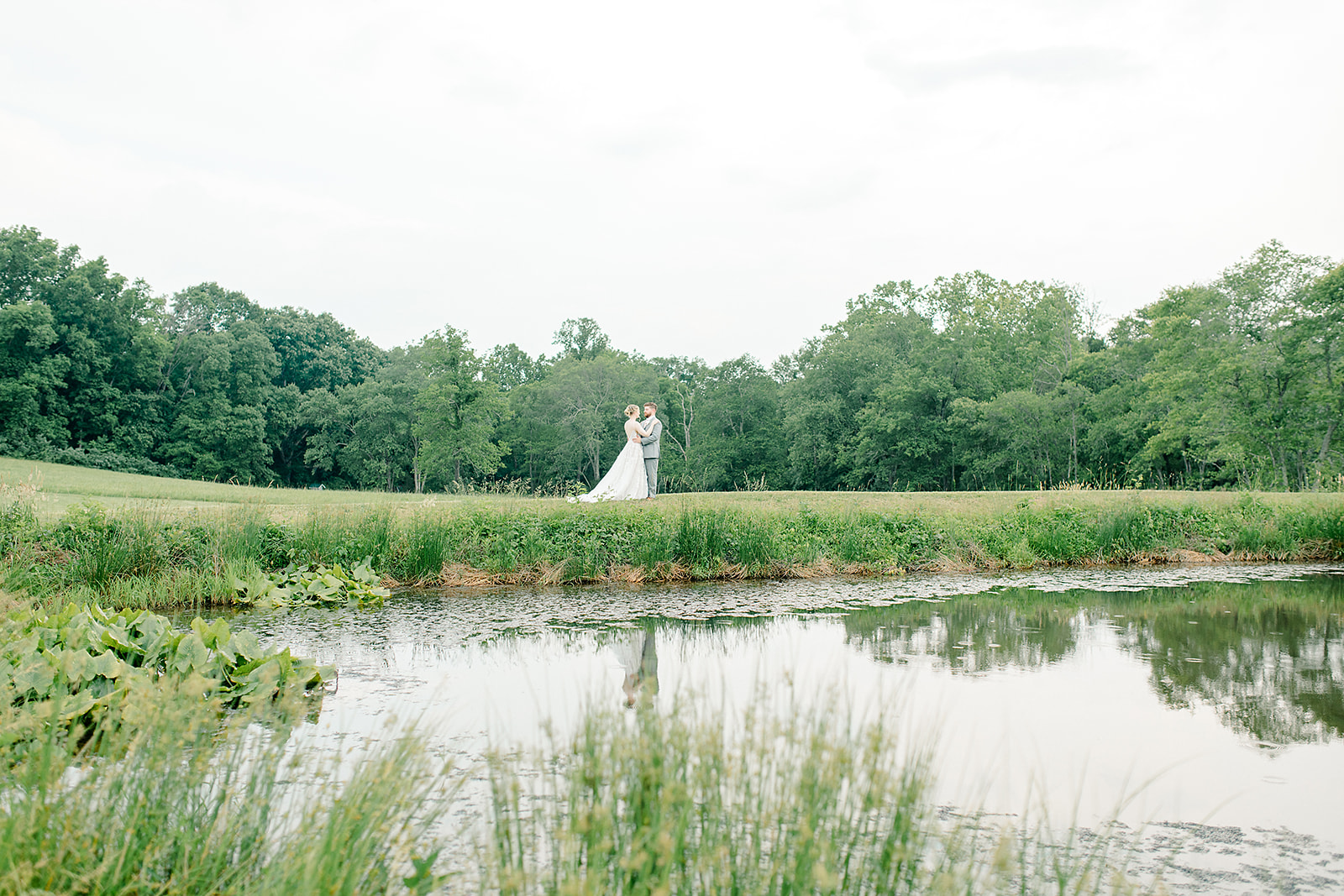 Couple standing near a lake holding each other after getting married, intimate wedding in virginia