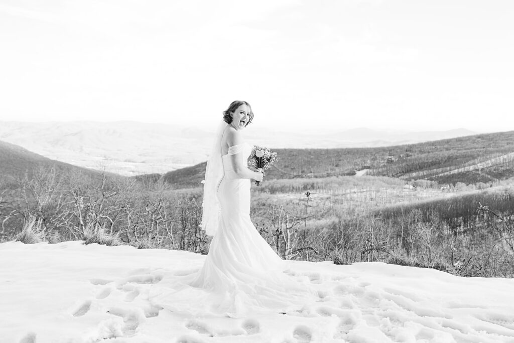A woman in a bridal gown, overlooking the mountains, standing in  feet of snow.