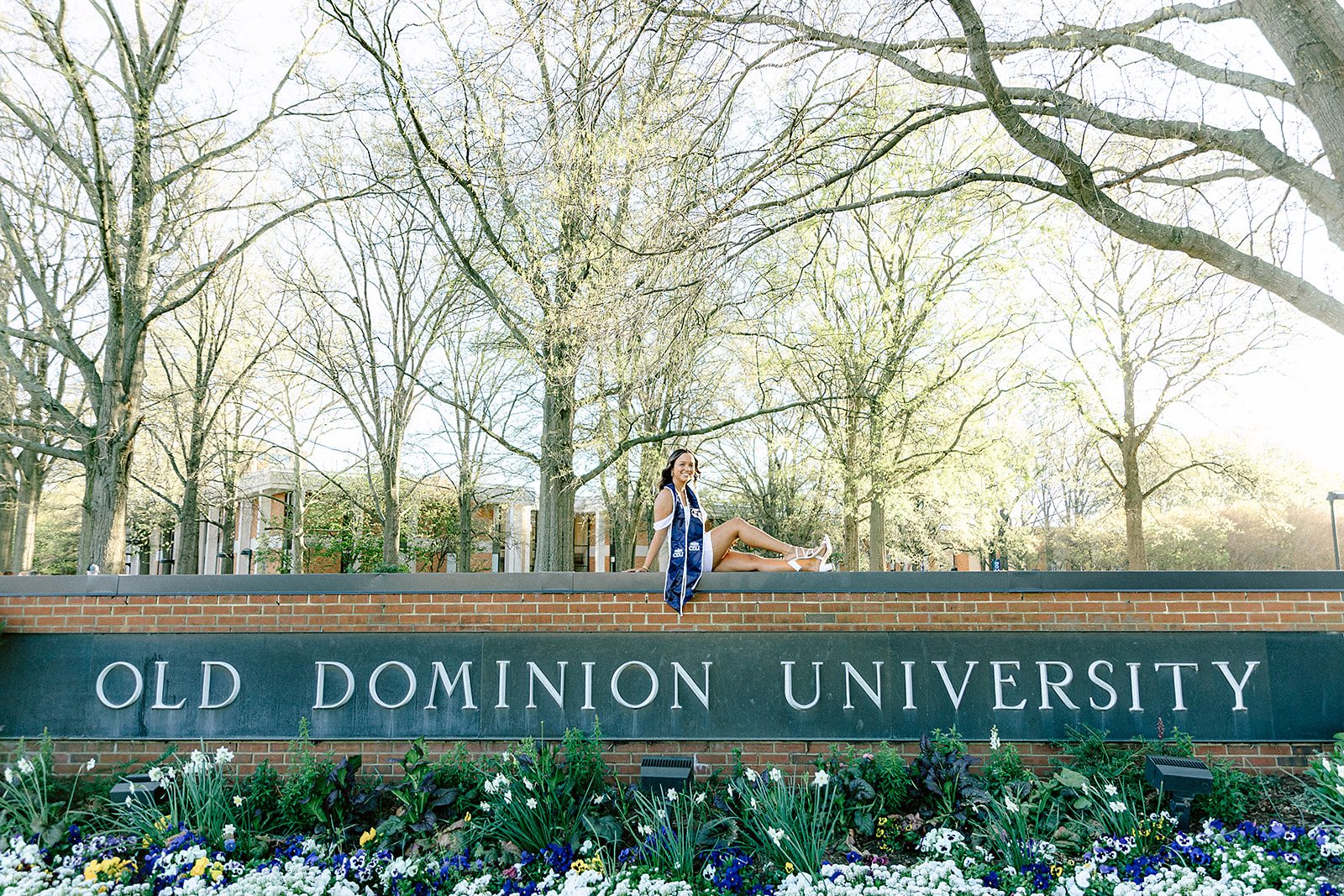 Young Woman sitting on the brick above Old Dominion University Campus Sign