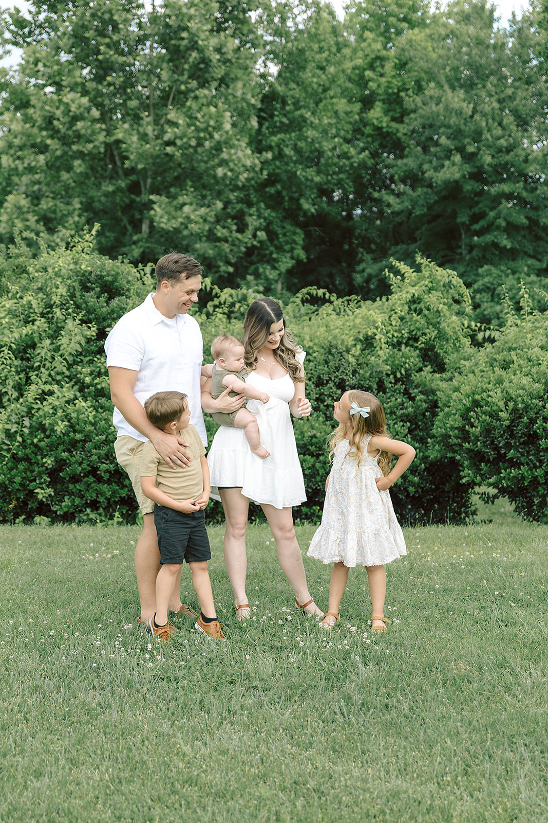 Family at a park standing in front of trees talking