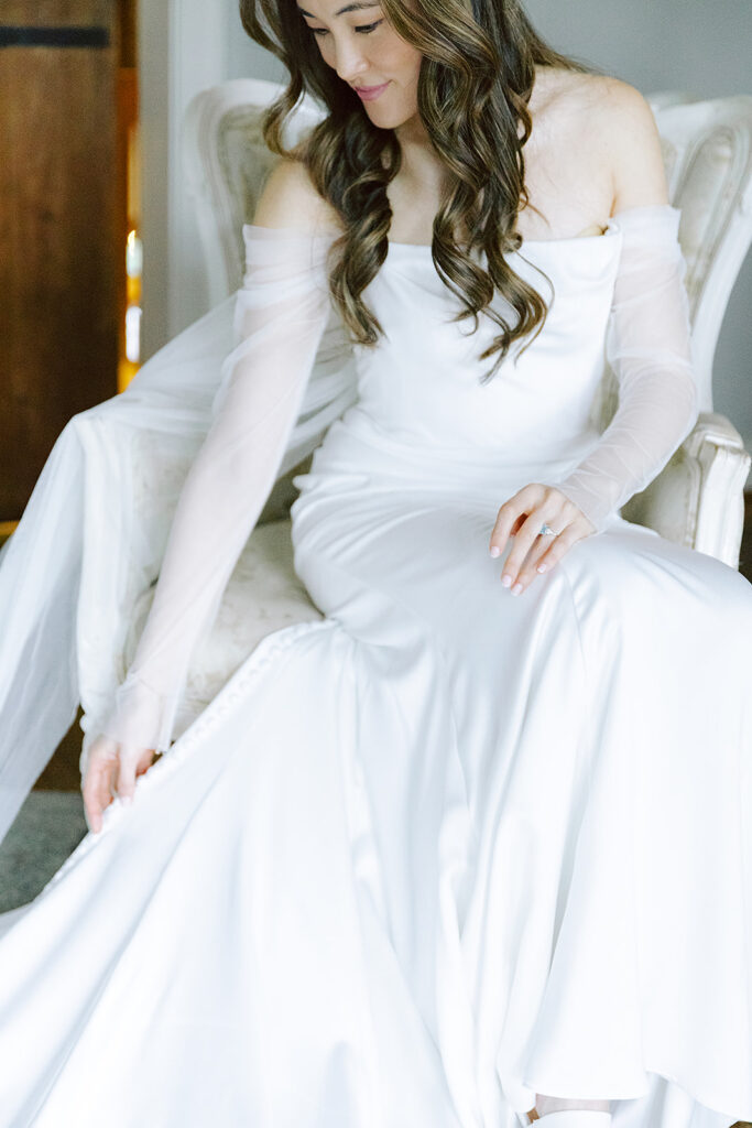 Bride adjusting her satin gown during a serene pre-ceremony moment at Bluemont Vineyard.