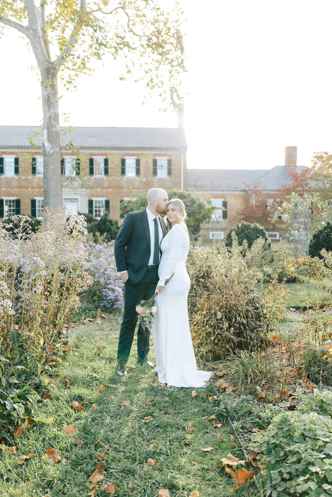 Couple posing in the garden at Chatham Manor, surrounded by colorful fall foliage and historic architecture in the background