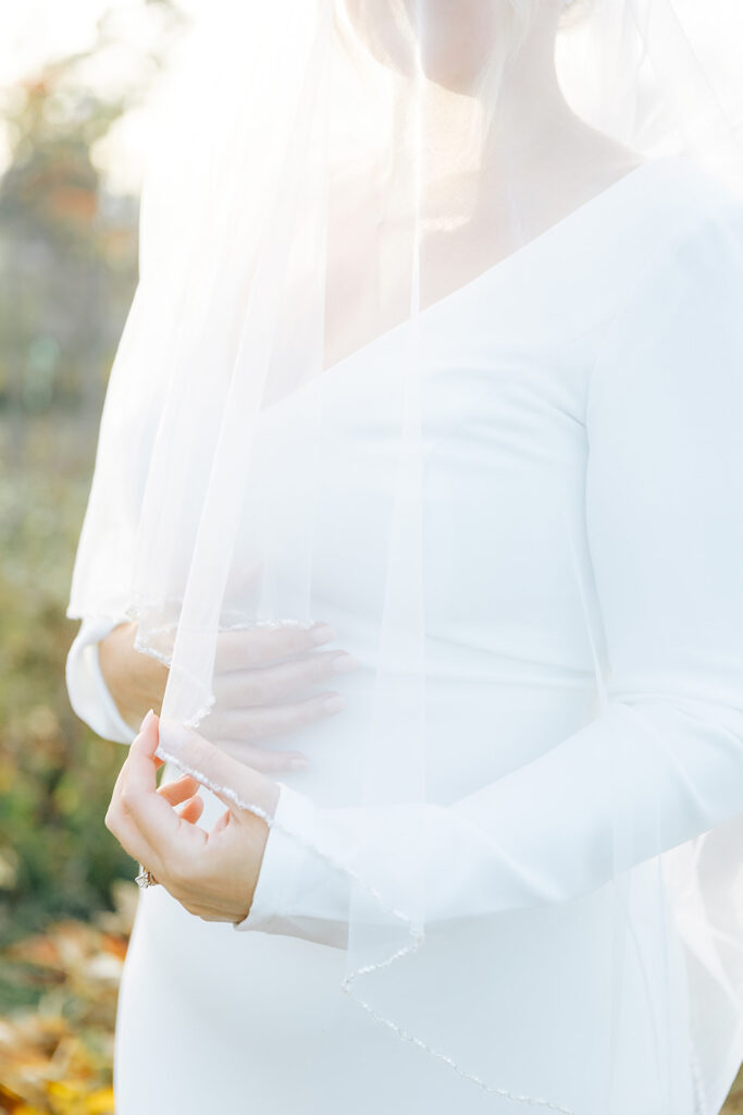 A close-up of a bride’s hands gently holding her delicate veil, highlighting the details of her white gown at Chatham Manor in Fredericksburg, Virginia.