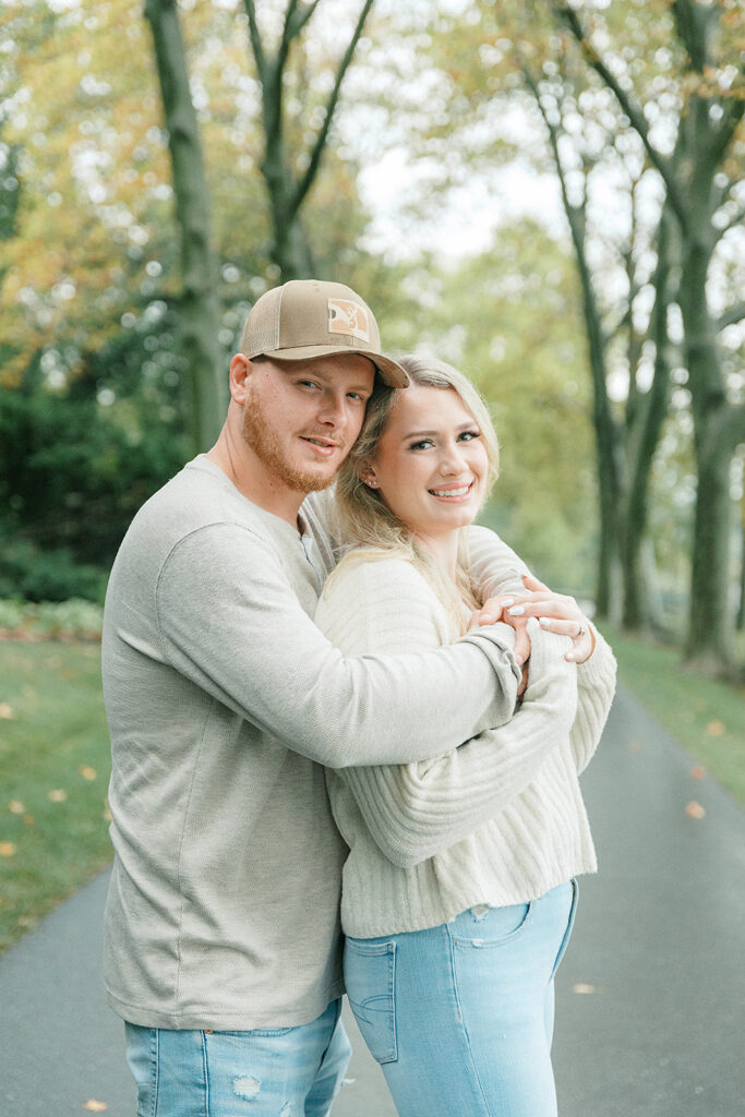 Couple standing together on a scenic tree-lined path, sharing a joyful embrace at Drumore Estate in Lancaster, PA.