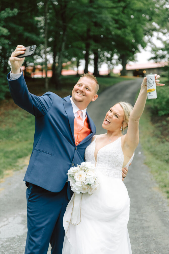 Bride and groom at Layz S Ranch taking a joyful selfie, celebrating their wedding with laughter and drinks on the tree-lined property.