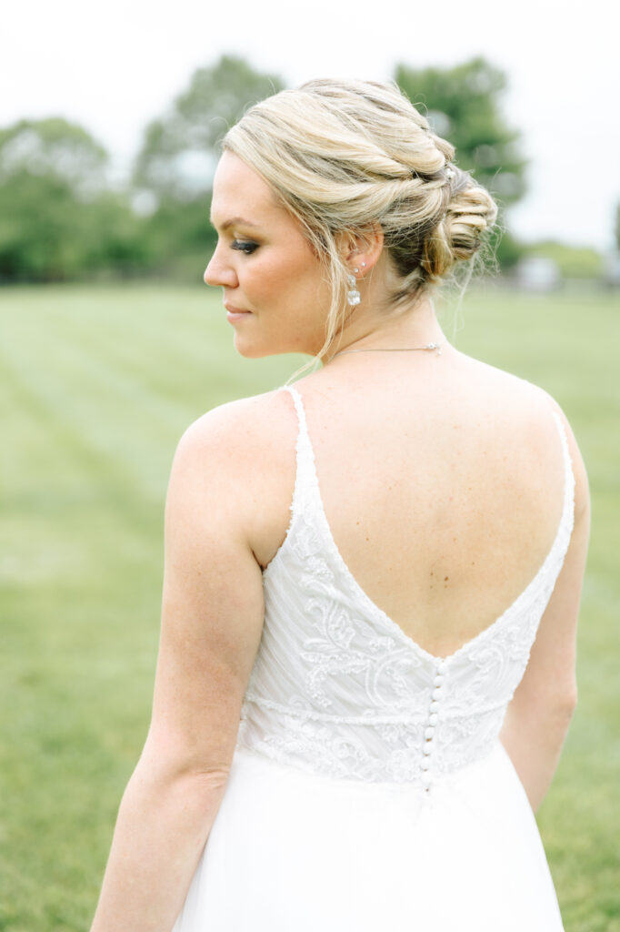 Close-up of the bride’s elegant updo and lace wedding gown, with the scenic green lawn at Layz S Ranch in the background.