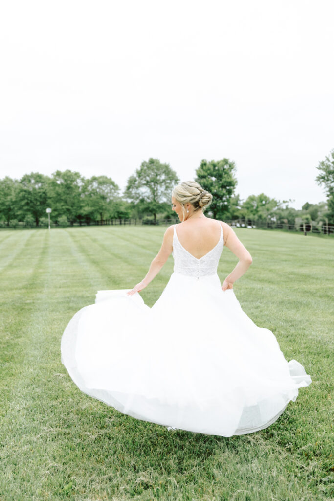 Bride twirling in her wedding gown on the lush green lawn at Layz S Ranch, framed by trees and the scenic countryside.