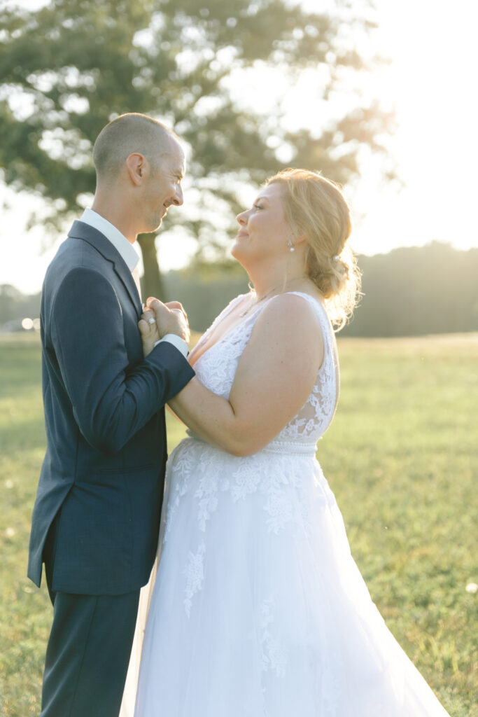 Bride and groom share a tender embrace during golden hour at Bowles Farm, with the sun casting a romantic glow over the scene.