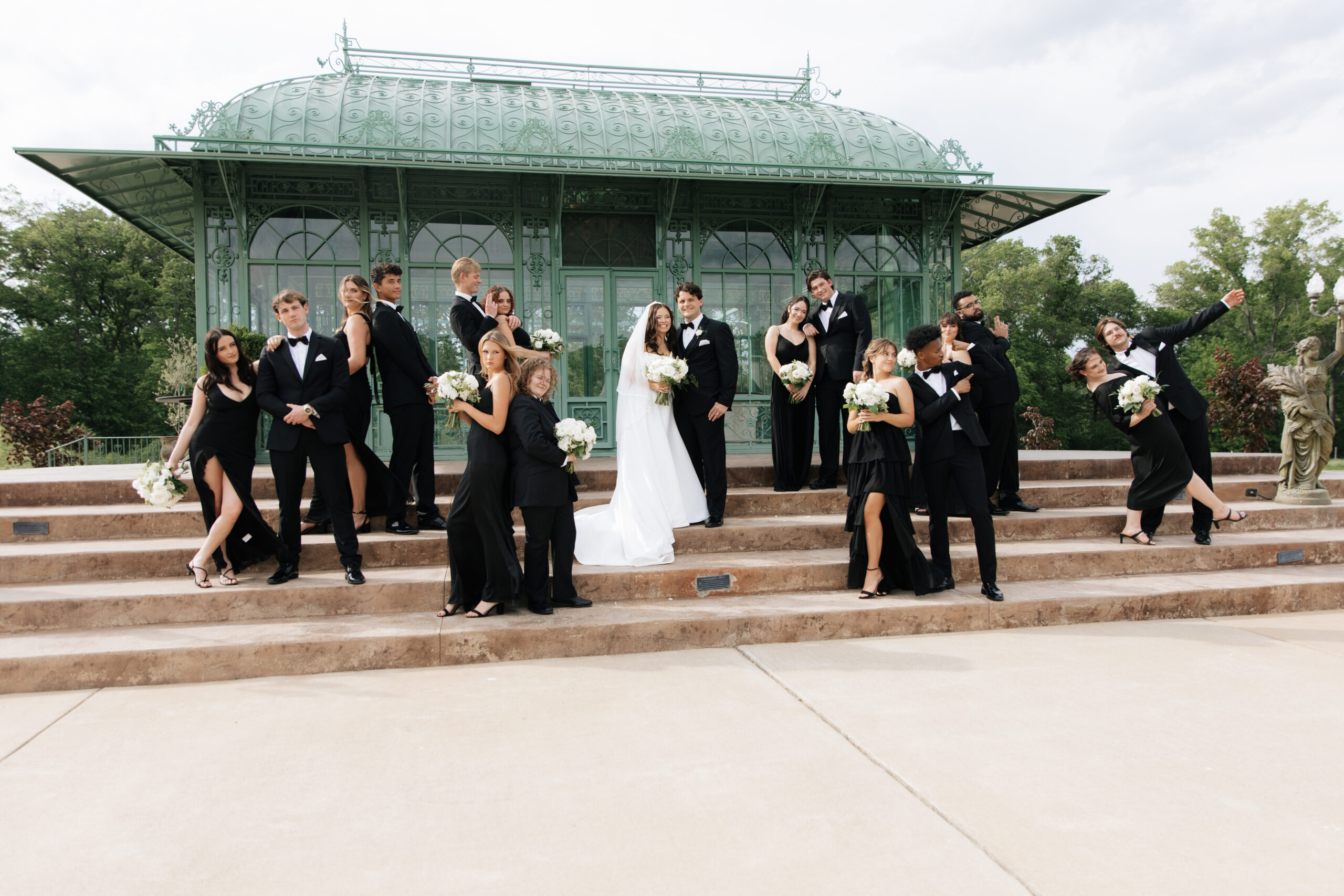 Editorial-style wedding party portrait on the pavilion steps at Morais Vineyards, with black formalwear and classic white florals