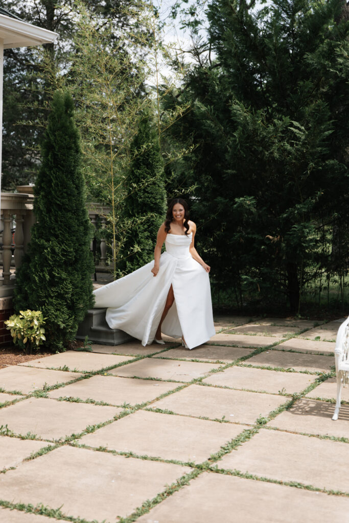 Bride stepping down stone stairs with flowing dress, surrounded by manicured greenery at Morais Vineyards.
