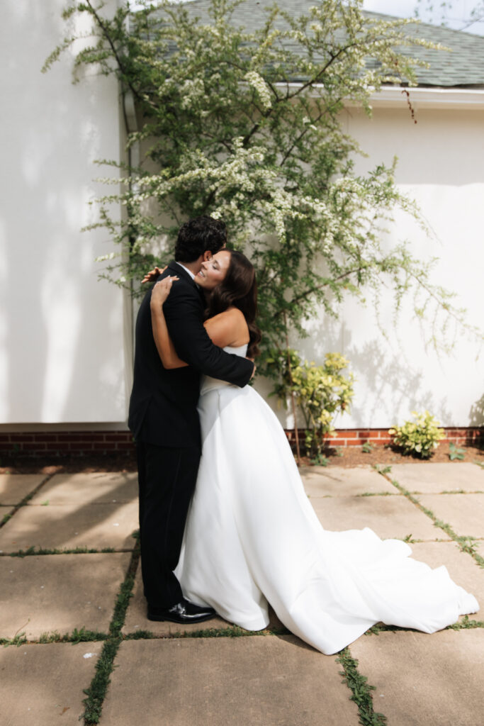 Bride and groom embracing joyfully during their first look outside the Morais Vineyards chapel.
